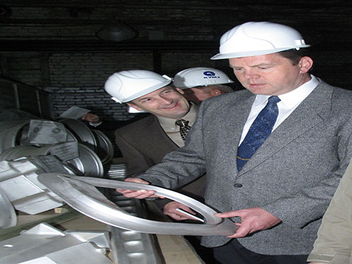 Team members in hard hats reviewing a manufactured part